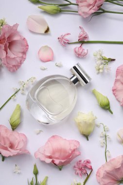 Parfüm ve çiçek dekoru beyaz arka planda, düz yerde.