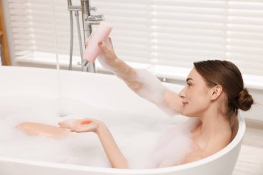 Kadın banyo jeli dökerken banyonun içine