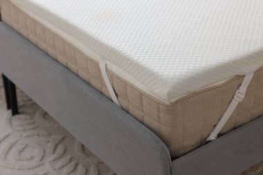 Gri yatakta beyaz köpüklü döşek.