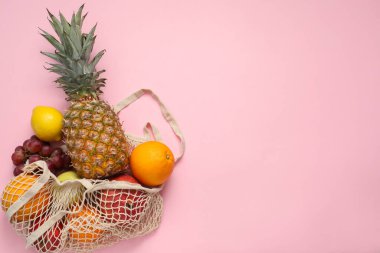 Pembe arka planda taze meyveler olan ip torbası, üst manzara. Metin için boşluk