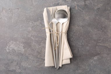 Gri desenli masa üzerinde şık çatal bıçak seti ve peçete.