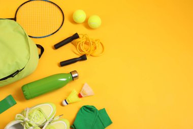 Sarı arka planda farklı spor aletleri, düz yatış. Metin için boşluk