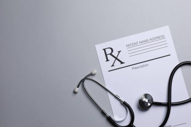 Tıbbi reçete formu ve açık gri arka planda steteskop, düz konum. Metin için boşluk