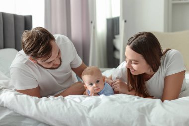 Mutlu bir aile. Anne babalar şirin bebekleriyle evde yatıyorlar.