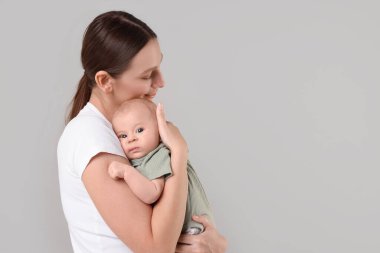 Anne, tatlı bebeği gri arka planda, mesaj için yer var.