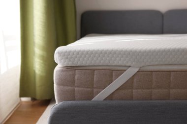 Beyaz hatıra köpüklü döşek üstü kapalı gri yatakta.