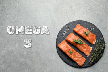 Omega 3. Taze kesilmiş somon, yeşillikler ve baharatlar gri masada, üst tarafta.