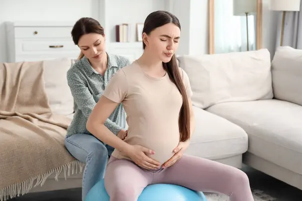 Doula working with pregnant woman at home. Preparation for child birth