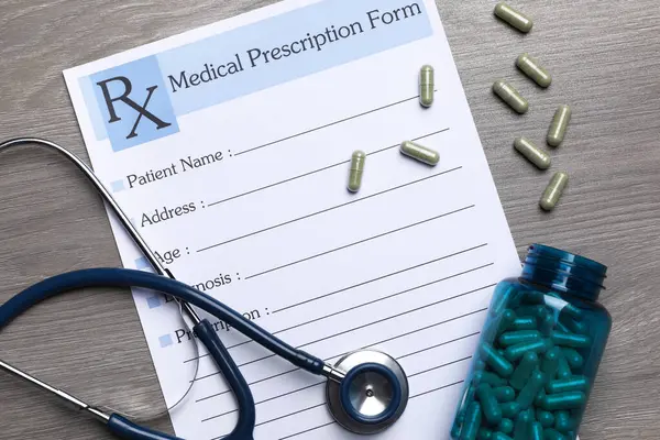 药方表格 听诊器和药丸放在木制桌子上 免版税图库照片