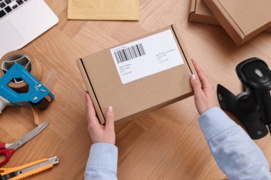 Postane çalışanı ahşap masada paket paketliyor.
