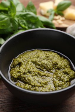 Lezzetli pesto sosu kasede fesleğen de ahşap masada, yakın plan.