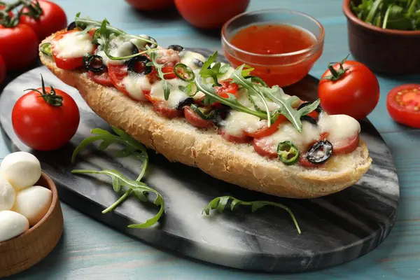 Tasty pizza toast and ingredients on light blue wooden table