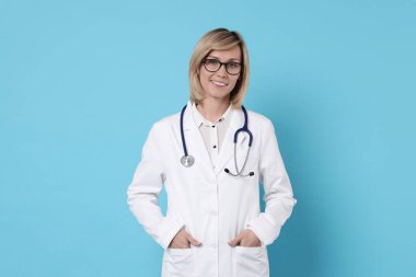 Açık mavi arka planda steteskoplu gülümseyen doktor.