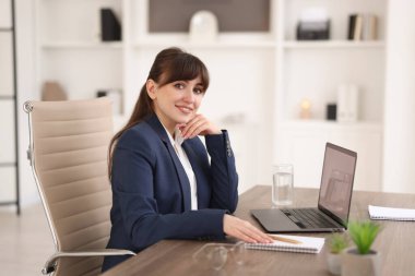 Ofisteki tahta masada Webinar izleyen bir kadın.