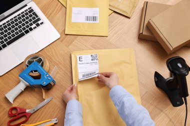 Paketleme. Postane çalışanı çantanın üstüne barkod yapıştırıyor.