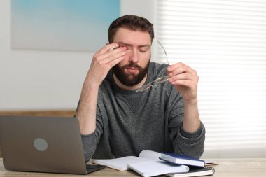 İçerideki masada dizüstü bilgisayarla oturan bunalmış bir adam.