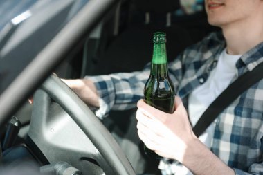 Bira şişesi sürücüsü arabası olan bir adam, yakın plan. İçkili araba kullanma.