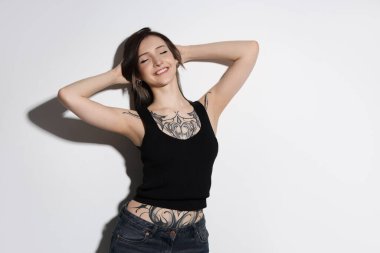 Açık arkaplanda gülümseyen dövmeli kadın portresi