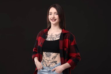 Siyah arka planda gülümseyen dövmeli kadın portresi