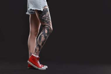 Siyah arka planda havalı dövmeleri olan bir kadın, yakın plan. Metin için boşluk