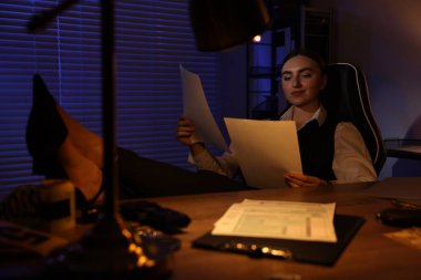 Geceleri masa başında belgelerle çalışan profesyonel dedektif.