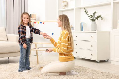 Anne kızına evde manyetik harflerle alfabe öğretiyor.