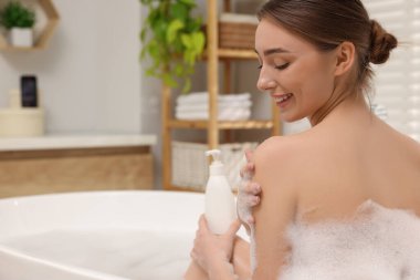 Banyoda duş jeliyle yıkanan bir kadın, mesaj atmak için yer.