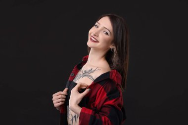 Siyah arka planda gülümseyen dövmeli kadın portresi