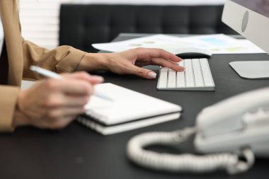 Secretary taking notes at table in office, closeup