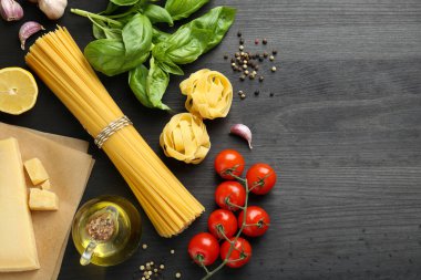 Farklı türde makarna, ürünler ve siyah ahşap masa üzerinde biber, düz yatak. Metin için boşluk