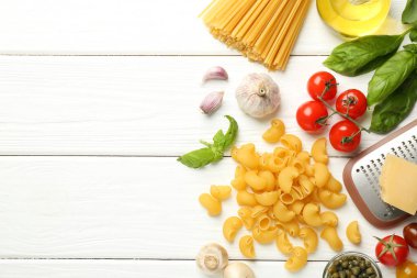 Farklı türde makarna, rende ve ürünler beyaz ahşap masa, düz yatak. Metin için boşluk