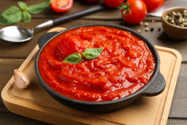 Ev yapımı domates sosu ve fesleğen, ahşap masada, yakın plan.