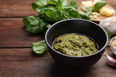 Lezzetli pesto sosu, fesleğen, sarımsak ve çam fıstığı ahşap masada, yakın plan.