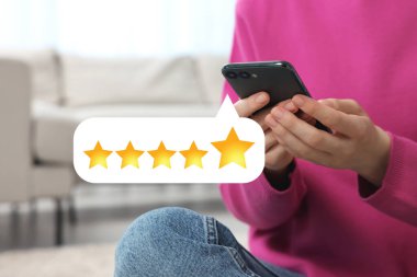 Woman leaving service feedback with smartphone at home, closeup. Stars over device