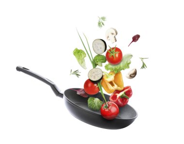 Kızartma tavası ve beyaz arka planda farklı sebzeler.