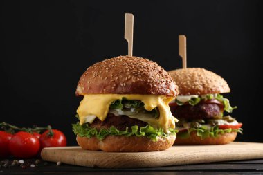 Siyah ahşap masada lezzetli köfteli vejetaryen hamburgerler, yakın plan.