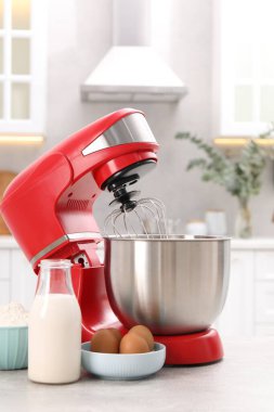 Modern kırmızı stand mikseri ve ürünler açık gri mutfak masasında
