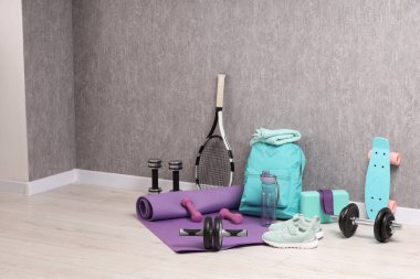 Gri duvarın yanında çok farklı spor aletleri var.