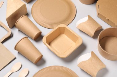 Çevre dostu gıda ambalajı. Açık gri arkaplanda kağıt kaplar ve sofra takımı