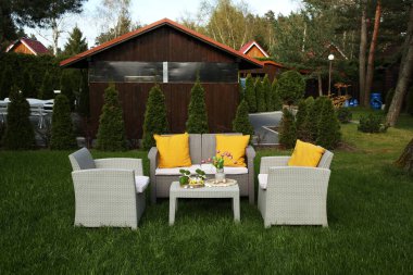 Paskalya süsleri. Vazodaki lale buketi, tavşan figürleri ve arka bahçedeki masada süslü yumurtalar.