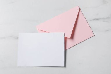 Beyaz mermer masa üzerinde boş kağıt ve mektup zarfı, üst görünüm