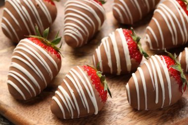 Delicious chocolate covered strawberries on wooden board, closeup