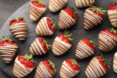 Delicious chocolate covered strawberries on wooden table, top view
