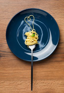 Kalp, ahşap masada çatal ve spagetti ile yapıldı.