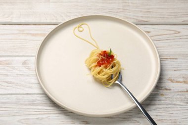Beyaz ahşap masada çatal ve spagetti ile yapılmış bir kalp.