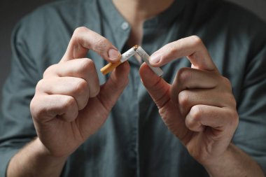 Stop smoking. Man holding broken cigarette, closeup