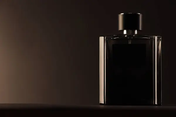 Luxury men`s perfume in bottle on table against dark background, space for text