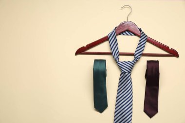 Hanger and neckties on beige background, flat lay. Space for text