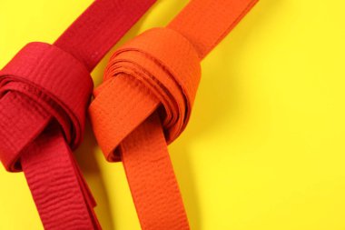 Sarı arka planda kırmızı ve turuncu karate kemerleri düz. Metin için boşluk