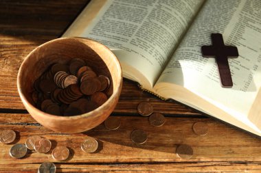 Bağış yap ve konsept ver. Tahta masada bozuk para, haç ve incil var.
